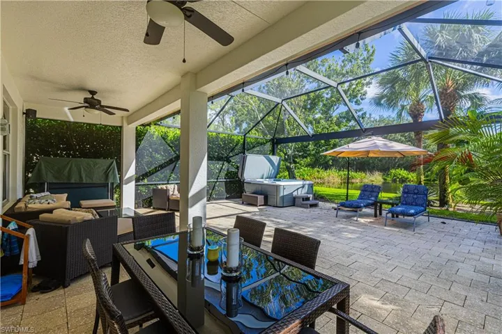 View of patio / terrace with an outdoor living space, ceiling fan, a hot tub, and a lanai