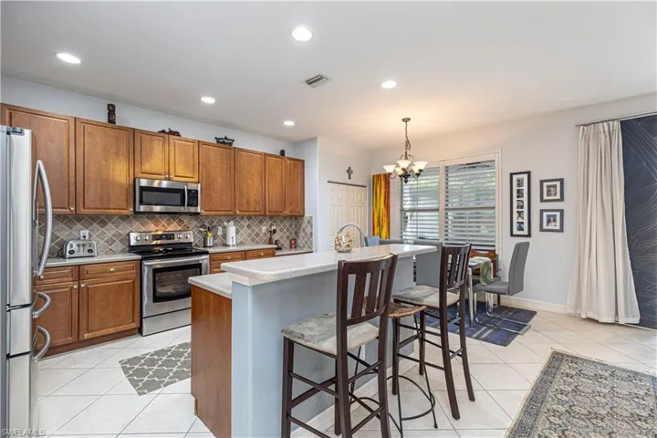Kitchen with an inviting chandelier, appliances with stainless steel finishes, a breakfast bar area, pendant lighting, and a kitchen island