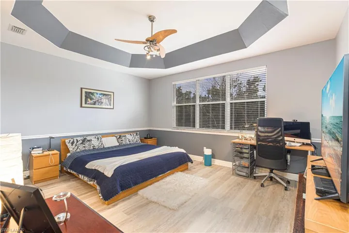 Bedroom featuring a tray ceiling, light hardwood / wood-style flooring, and ceiling fan
