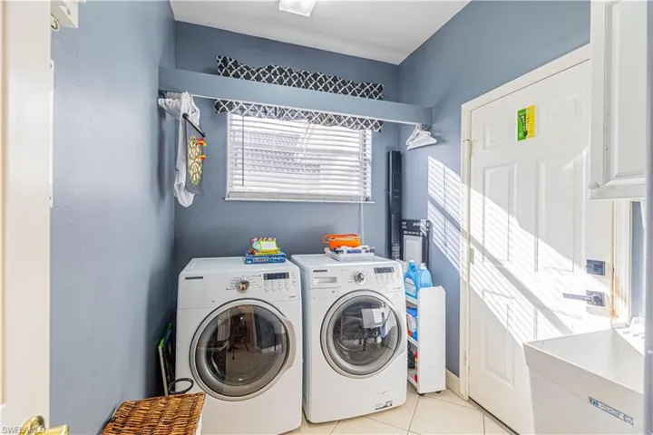 Laundry area featuring washing machine and dryer and light tile patterned floors