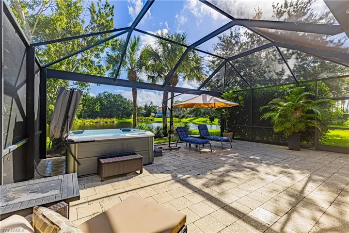 View of patio featuring glass enclosure and a hot tub
