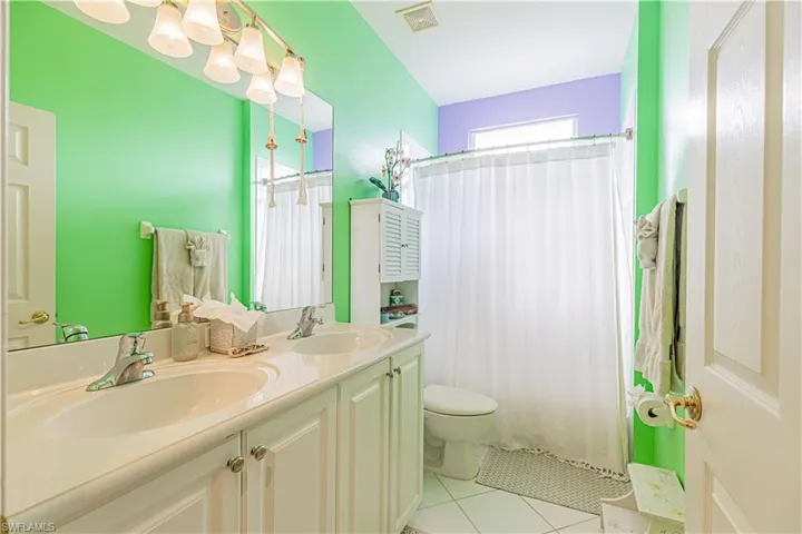 Bathroom with a shower with shower curtain, vanity, toilet, and tile patterned floors