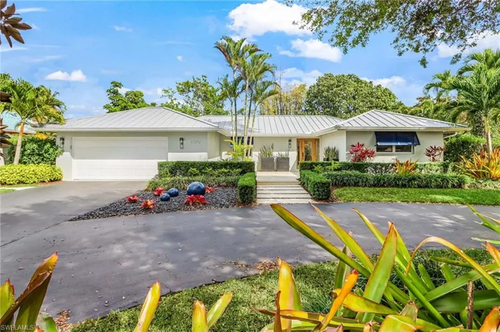 Ranch-style home featuring a garage, stucco siding, a standing seam roof, and concrete driveway
