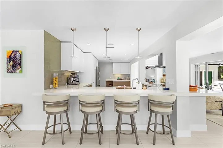 Kitchen with white cabinetry, a peninsula, decorative backsplash, modern cabinets, and a breakfast bar area