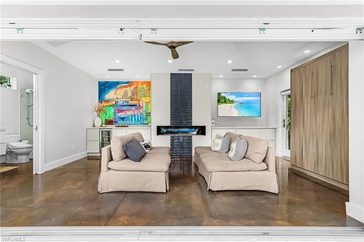 Living area with finished concrete flooring, recessed lighting, wine cooler, and a ceiling fan