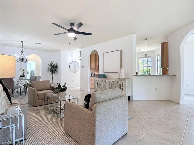 Living area with arched walkways, a chandelier, light tile patterned floors, and a ceiling fan