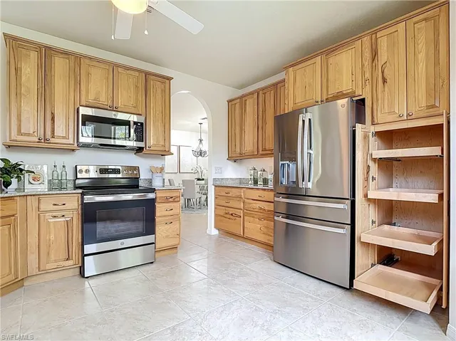 Kitchen featuring stainless steel appliances, arched walkways, open shelves, a ceiling fan, and light tile patterned floors