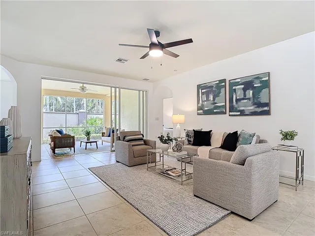 Living room with arched walkways, ceiling fan, and light tile patterned floors
