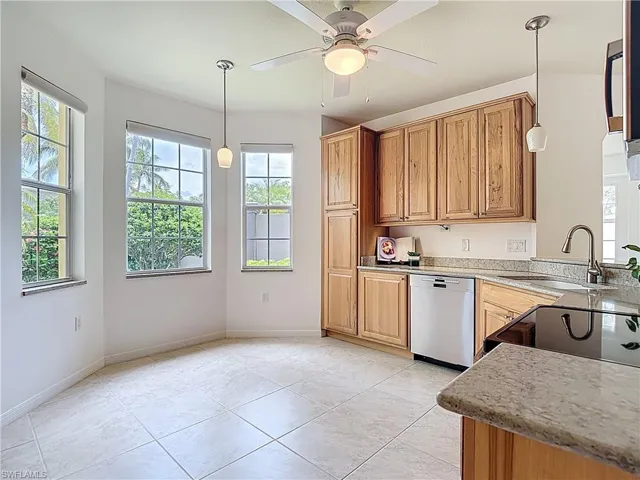 Kitchen featuring dishwasher, light stone counters, pendant lighting, a ceiling fan, and light tile patterned floors