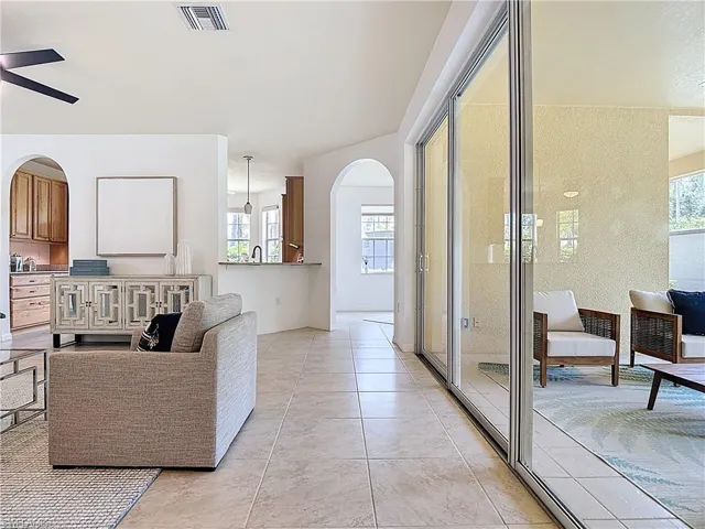 Living room featuring arched walkways, healthy amount of natural light, a ceiling fan, and light tile patterned floors