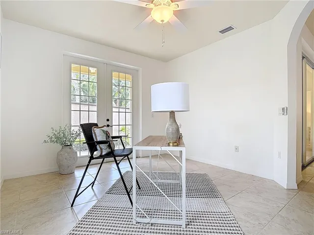 Office area featuring french doors, arched walkways, and ceiling fan