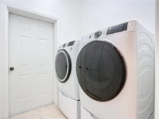 Laundry area with washer and dryer and light tile patterned floors