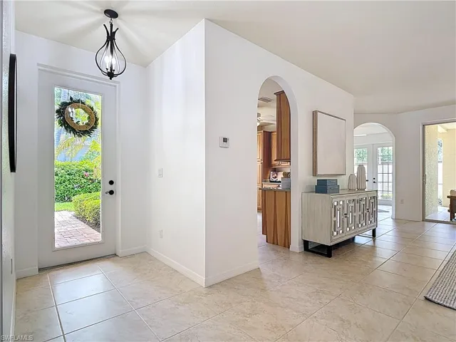 Foyer entrance featuring arched walkways, light tile patterned flooring, and a chandelier