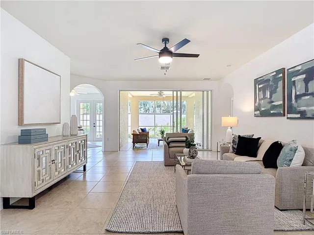 Living area with arched walkways, light tile patterned floors, and ceiling fan