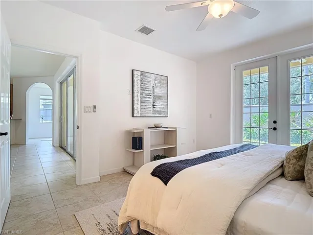 Bedroom with access to exterior, arched walkways, french doors, and a ceiling fan