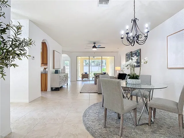 Dining room featuring a ceiling fan, arched walkways, light tile patterned floors, and a chandelier