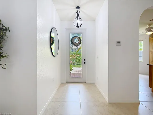 Foyer featuring healthy amount of natural light, a ceiling fan, light tile patterned floors, and arched walkways