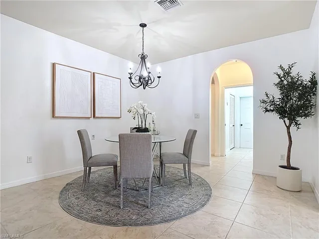 Dining area with arched walkways, a chandelier, and light tile patterned floors