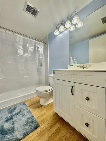 Full bath with vanity, a stall shower, and light wood finished floors