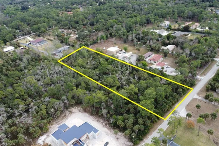 Aerial perspective of suburban area featuring property parcel outlined and a heavily wooded area