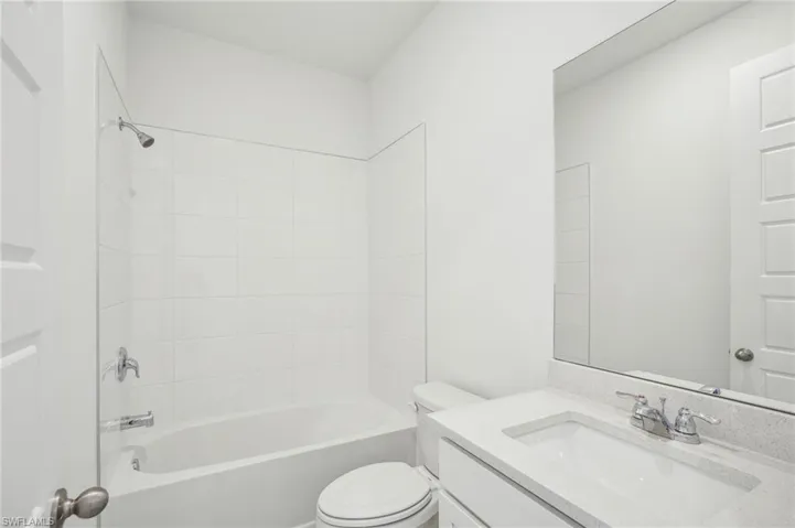 Full bathroom with tiled shower / bath combo, vanity, and toilet