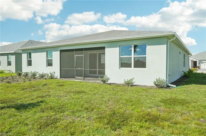 Back of house featuring a lawn and a sunroom