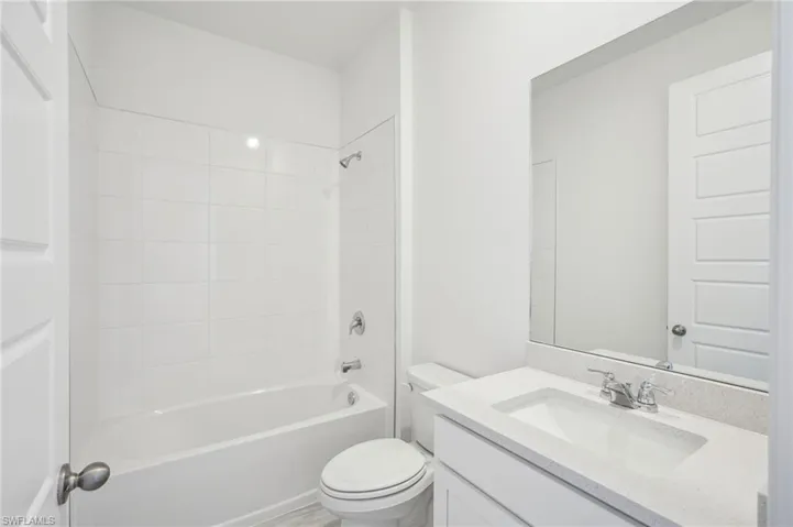 Full bathroom with tiled shower / bath, vanity, and toilet