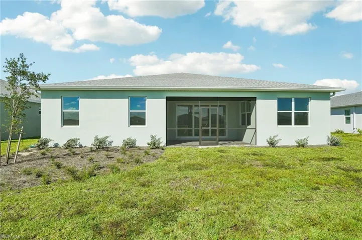 Rear view of property featuring a sunroom, a yard, and a patio