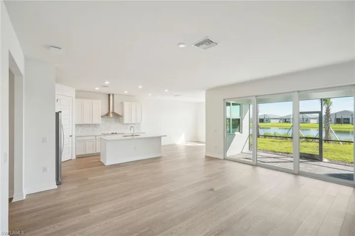 Unfurnished living room with light wood-type flooring, sink, and a water view