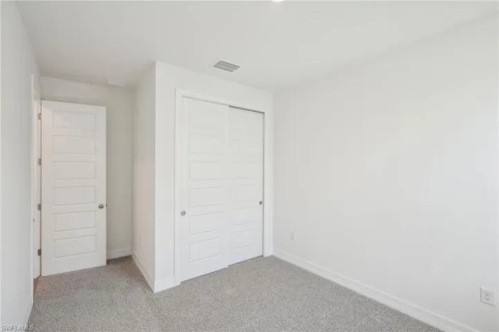 Unfurnished bedroom featuring light carpet and a closet