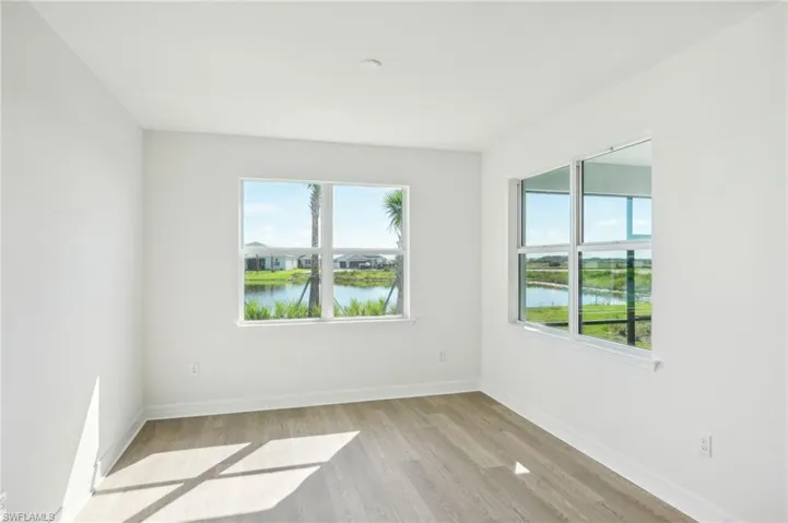 Unfurnished room featuring light hardwood / wood-style flooring, a water view, and a wealth of natural light