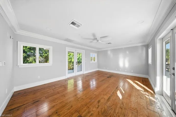 Spare room featuring french doors, a ceiling fan, hardwood / wood-style flooring, and ornamental molding