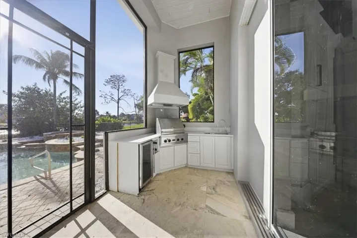Unfurnished sunroom with beverage cooler and a sink