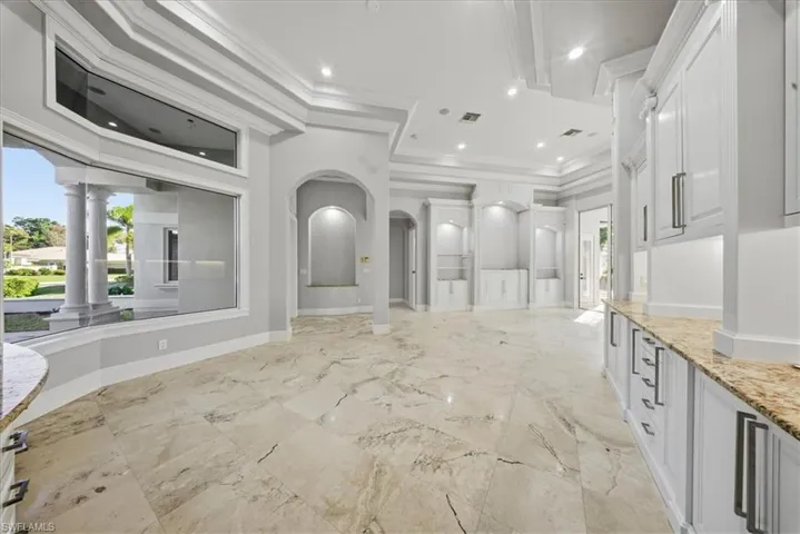 Bathroom with crown molding, vanity, a tray ceiling, recessed lighting, and light marble finish floors