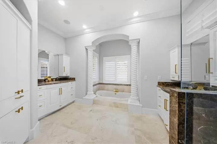 Bathroom with vanity, a bath, ornamental molding, ornate columns, and recessed lighting