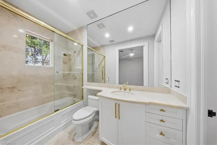 Full bath with combined bath / shower with glass door, vanity, and recessed lighting