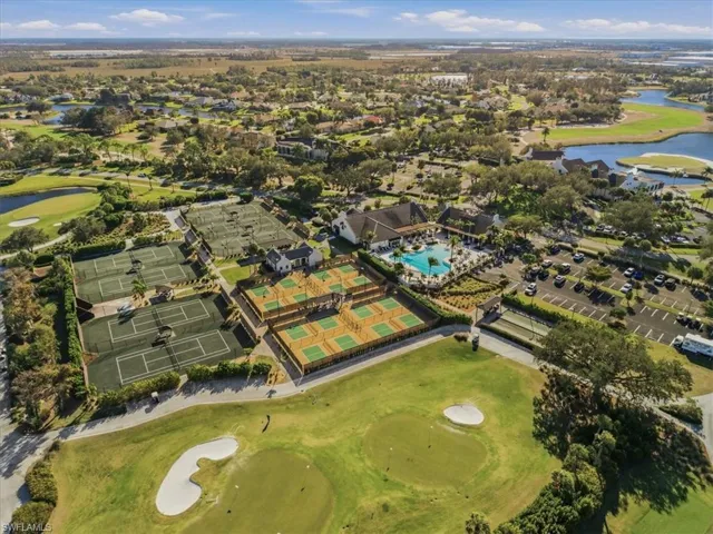 Aerial view of property and surrounding area featuring a golf club and a nearby body of water