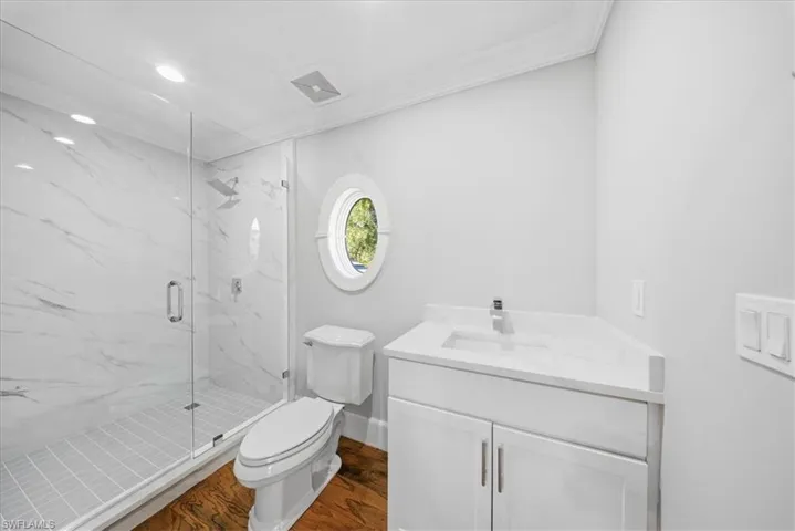 Bathroom with vanity, a marble finish shower, dark wood-style flooring, ornamental molding, and recessed lighting