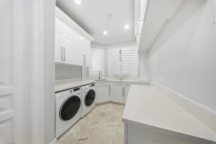 Laundry area with cabinet space, washer and dryer, crown molding, and recessed lighting