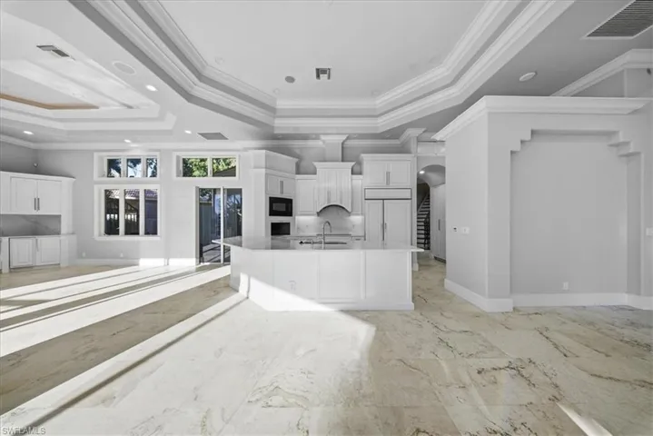 Kitchen featuring open floor plan, crown molding, arched walkways, a large island, and built in appliances