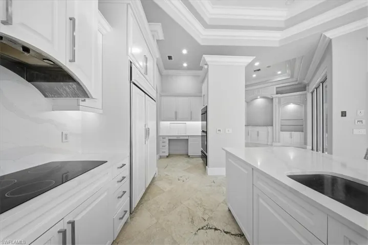 Kitchen featuring white cabinetry, light stone counters, black electric stovetop, paneled built in fridge, and recessed lighting