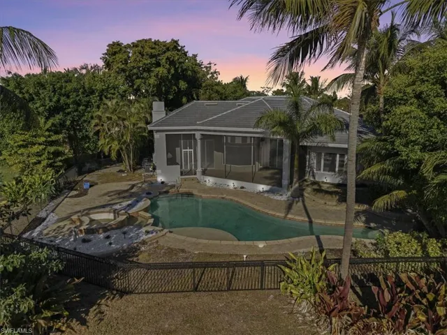 Back of property at dusk with a sunroom, a chimney, and a patio