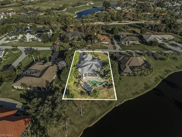 Aerial perspective of suburban area with a large body of water, property parcel outlined, and a golf course
