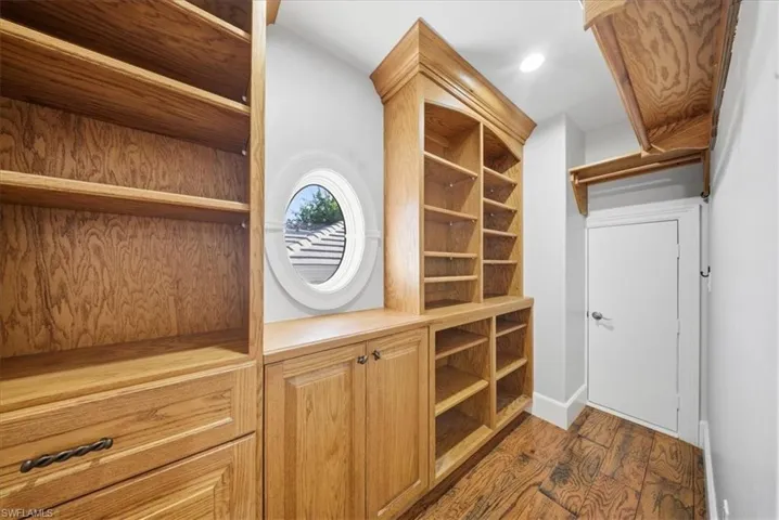 Walk in closet with dark wood-style floors