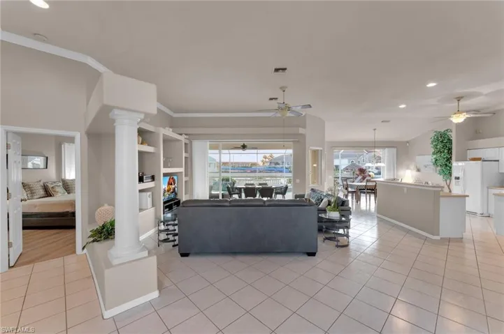 Living room featuring decorative columns and light tile patterned flooring