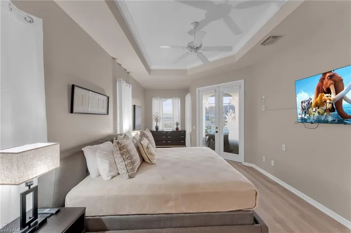 Bedroom with access to exterior, ornamental molding, a tray ceiling, ceiling fan, and light hardwood / wood-style floors