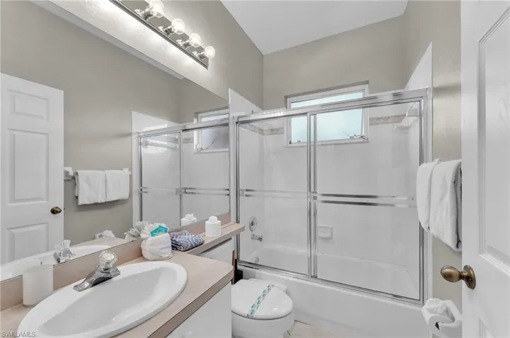 Full bathroom with vanity, enclosed tub / shower combo, and toilet