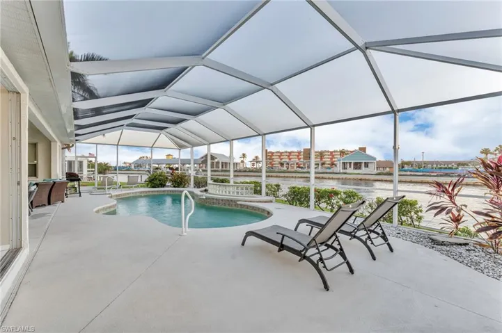 View of swimming pool featuring glass enclosure and a patio