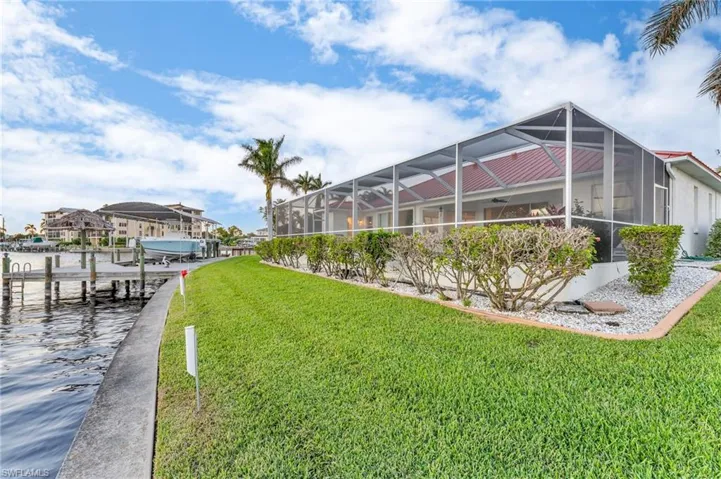 View of yard with a lanai, a water view, and a boat dock