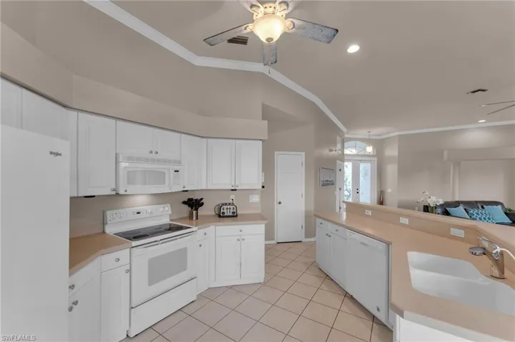 Kitchen with french doors, sink, white cabinets, and white appliances